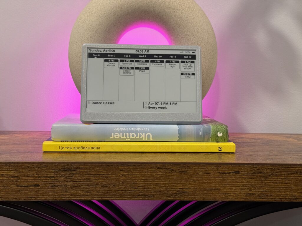 E-ink calendar week view propped on a stack of books