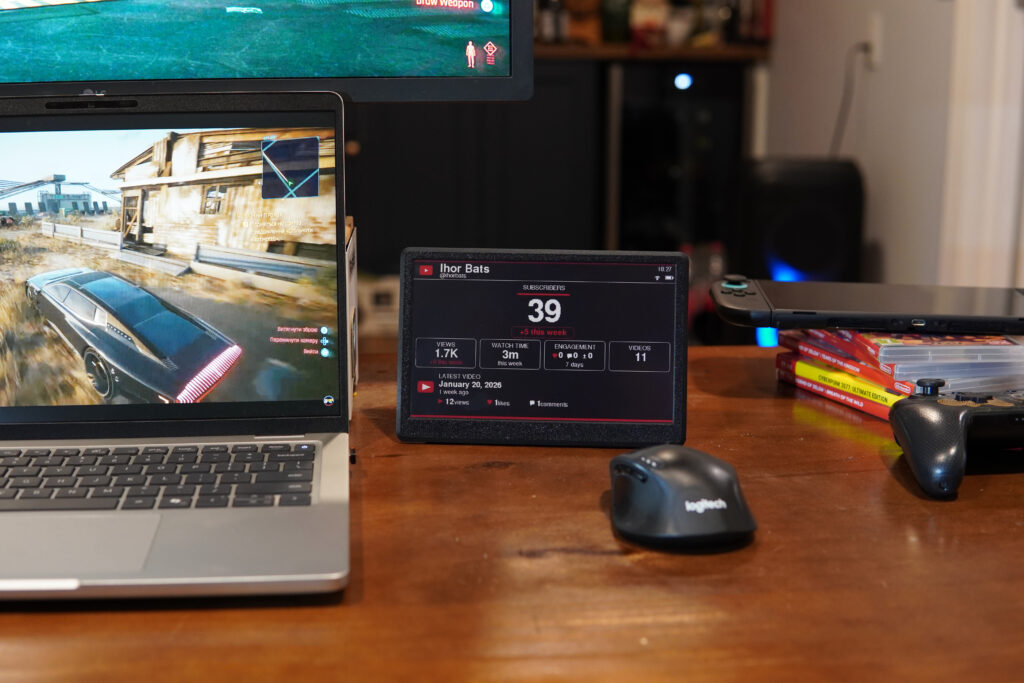 YouTube subscriber counter on a desk next to a laptop and mouse